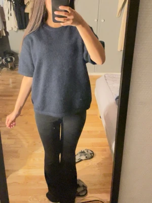 Mörkblå stickad t-shirt - Mörkblå stickad t-shirt med korta ärmar och rund hals. Oversized passform som ger en avslappnad look. Perfekt att styla med jeans eller kjol för en trendig vibe.