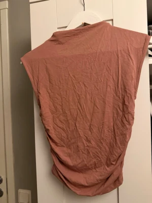 Rosa ärmlös topp från Gina Tricot - Snygg rosa topp från Gina Tricot i mjuk bomull. Modellen är ärmlös med avslappnad passform och rund halsringning. Perfekt att styla med jeans eller kjol för en trendig look.