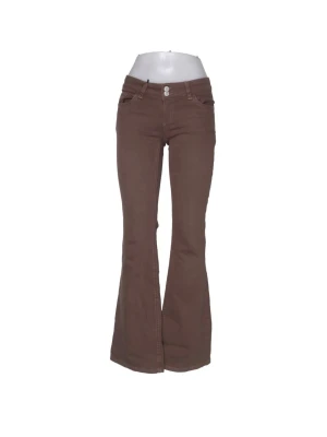 Bruna bootcut jeans med låg midja - Snygga bruna bootcut jeans med låg midja och klassiska fem fickor. Jeansen har utsvängda ben och dubbla knappar framtill. Perfekta för dig som gillar retrostil och vill sticka ut lite extra.