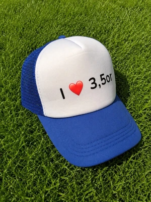 Blå och vit keps med text - Snygg keps med blå skärm och nät samt vit frontpanel med trycket 'I ❤️ 3,5or'. Perfekt för dig som gillar unika statements. Justerbar baktill för bästa passform.