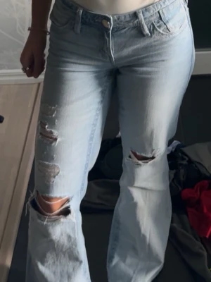 Ljusblå slitna jeans - Säljer ett par ljusblå jeans med raka ben och flera slitningar på låren och knäna. Jeansen är lågmidjade och är i storlek S från Gina Tricots 14+ 💕💕 de är används men har inga deffekter, endast att hålet på vänstra benet har blivit lite större.