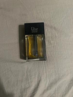 Dior Homme Intense Eau de Parfum - Dior Homme Intense är en lyxig herrparfym med elegant design. Flaskan är rektangulär i genomskinligt glas med svart lock och synlig spraydel. Doften är känd för sina varma, träiga och blommiga toner. Perfekt för dig som vill sticka ut med en sofistikerad signaturdoft.