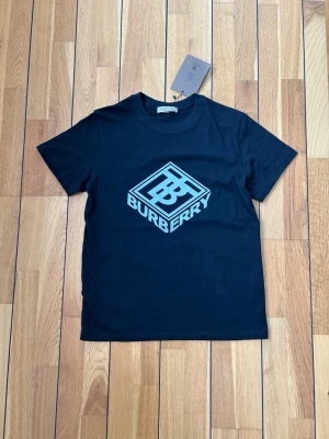 Svart Burberry t-shirt i bomull - Snygg svart t-shirt från Burberry med klassisk rund halsringning och diskret logga. Tillverkad i mjuk bomull som känns skön mot huden. Perfekt för dig som gillar stilrena och exklusiva plagg från London.