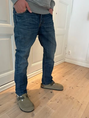 (Sjuk fade)Blå jeans från Levi's - Klassiska blå jeans från Levi's med rak passform och fem fickor. Jeansen har en snygg tvätt och subtila slitningar för en avslappnad look. Tillverkade i denim med tydliga sömmar och Levi's ikoniska bakficka med logotyp.