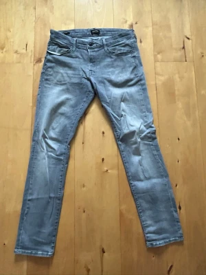 Jack&Jones Slim Glenn Jeans - Ljusgråa jeans från Jack and Jones i modellen slim glenn, alltså sitter dem slimfit. Storlek 33/32. Jag är 185cm och väger 80kg. Hör av dig vid fler frågor😁
