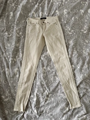 Beige skinny jeans från Maison scotch  - Snygga beige skinny jeans från Maison scotch med klassisk femficksdesign och dragkedjegylf. Jeansen har smal passform och är tillverkade i ett stretchigt material som sitter tajt längs benen. Perfekta för en trendig och avslappnad look.