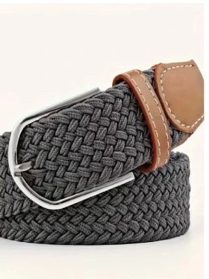 Grått flätat bälte med skinn-detaljer - Snyggt grått flätat bälte med bruna skinn-detaljer och silverfärgat spänne. Perfekt accessoar för att lyfta din outfit med en modern touch. Bältet har en klassisk design och passar till många olika stilar.