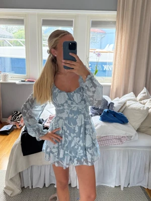 Blå blommig klänning  - Säljer denna blåa klänningen med inbyggda shorts och knyt i bak. Perfekt nu till sommaren!! Från Marshall’s i usa. Helt i nyskick!!