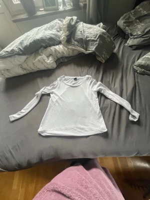 Vit långärmad topp - En basic vit långärmad topp med rund halsringning. Perfekt att styla med jeans eller kjol för en enkel och clean look. Tunt och mjukt material som känns skönt mot huden.