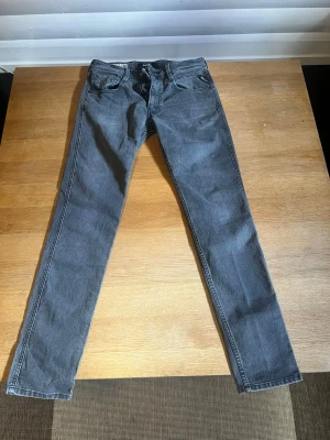 Grå smala jeans från Replay anbass - Snygga grå jeans från  Replay med smal passform och klassisk femficksdesign. Jeansen har svarta sömmar och diskret logga på bakfickan. Tillverkade i mjuk denim som sitter skönt hela dagen.