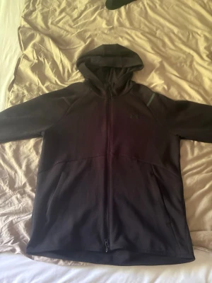 Svart hoodie  - Säljer en svart hoodie med dragkedja framtill och två sidofickor. Hoodien har en klassisk huva och är tillverkad i ett mjukt och bekvämt material, perfekt för chill dagar eller träning. Diskret logga på bröstet och snygg passform.