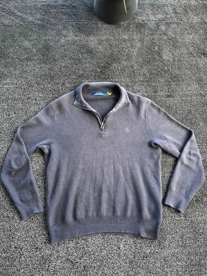 Ralph Lauren half zip - Klassisk grå stickad tröja från Polo Ralph Lauren med halv dragkedja och broderad logga på bröstet. Tröjan har lång ärm, ribbade muddar och krage. Perfekt till lager på lager och enkel att matcha med olika outfits. Storlek L men passar mer som M, skick 8/10 lite solblekt. Pris går att diskutera✅