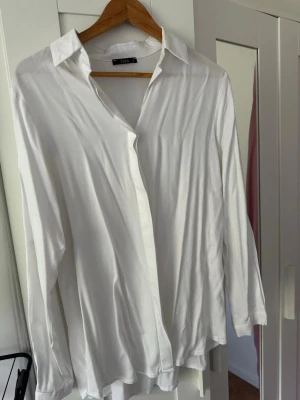 Vit skjorta från Zena i storlek L - Klassisk vit skjorta från Zena i storlek L. Skjortan har lång ärm, krage och knäppning framtill. Perfekt för en clean och stilren look. Tillverkad i ett mjukt och lätt material som känns skönt mot huden.