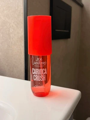Sol de Janeiro Carioca Crush  - Fräsch parfym från Sol de Janeiro i doften Carioca Crush. Flaskan är genomskinlig orange med vit spraypump och matchande orange lock. Perfekt att ha med i väskan för en tropisk touch när du vill dofta extra gott.