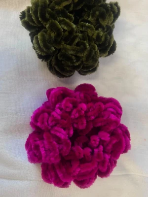 Fyra fluffiga scrunchies i olika färger - Säljer ett set med fyra scrunchies i sammet, formade som stora fluffiga blommor. Färgerna är mörkgrön, ceriserosa, röd och klarblå. Perfekta för att ge håret en färgklick och volym. Materialet är mjukt och elastiskt, vilket gör dem skonsamma mot håret. En styck för 35kr
