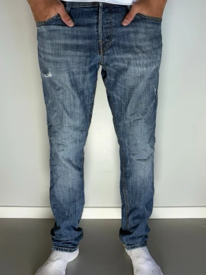 Blå slitna jeans med rak passform Jack & Jones - Tjeeena! Vi säljer nu detta par blå jeans med rak passform och lätt slitna detaljer från Jack & Jones. Jeansen har klassisk femficksdesign, dragkedjegylf och kontrastsömmar. Materialet är denim i bomull och färgen är tvättad blå med slitningar på låret. Bara att höra av dig vid frågor! Tack på förhand MVH CarsliCloset! 💙