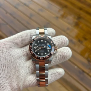40mm Seiko Rootbeer GMT Mod - Tja! Säljer en Seiko Rootbeer GMT Mod! Använda en gång på armen men är såklart i nyskick. Om klockan: NH34 automatisk GMT rörelse. 904L Stainless Steel. C3 Lume (lyser i mörkret). Verktyg till länkar ingår. En jättefin klocka för vem som helst!