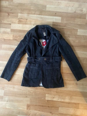 Svart jeansjacka med bälte från H&M - Fitted denim jacka i bomull med avtagbart bälte. Jackan har två stora fickor framtill. Storlek L men sitter som M.