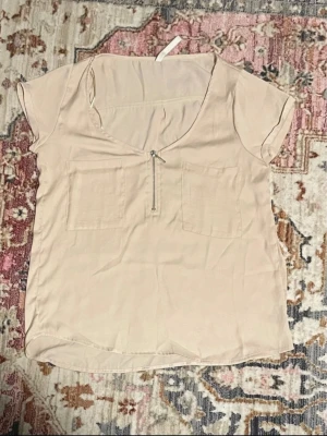 Beige kortärmad blus med dragkedja Stradivarius  - beige blus med korta ärmar och två bröstfickor. Storlek S
