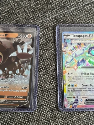 Fyra Pokémonkort i plastfickor - Säljer fyra Pokémonkort: Ursaluna V, Terapagos ex, Crabominable V och Coalossal VMAX. Korten har färgstarka illustrationer och ligger i genomskinliga plastfickor. Perfekt för samlare eller dig som vill utöka din Pokémonkort-lek.          Skriv ifall ni vill köpa separata 