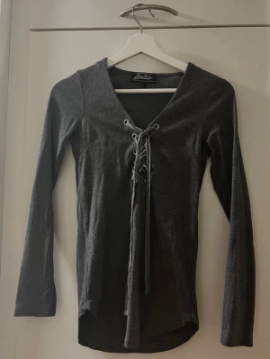 Grå långärmad tröja från Miss Milla - Storlek S - Snygg grå långärmad tröja från Miss Milla! Dekorativ snörning framtill. V-ringad. Svensk design. Material: 52 % Bomull, 43 % Polyester och 5 % Elastan. Storlek: S. Säljs i bra skick! Kika gärna in på mina andra annonser, jag säljer just nu flera klädesplagg! Hör av dig vid intresse eller frågor!