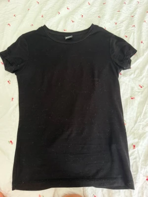 Svart basic t-shirt från Gina Tricot - En enkel svart t-shirt från Gina Tricot i storlek XS. T-shirten har rund halsringning och korta ärmar. Tillverkad i mjuk bomull som passar perfekt till alla outfits. Klassisk och stilren modell.