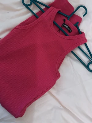 Svart långärmad ribbad klänning - En svart, långärmad klänning från Umbro i ribbat material. Klänningen har en kroppsnära passform och en snygg, något fyrkantig ringning. Perfekt för dig som gillar stilrena och enkla plagg med en modern twist.