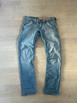 Ljusblåa jeans från disel - Säljer ett par ljusblå jeans från  diseö med raka ben och låg midja. Jeansen har tydliga sömmar, fem fickor och coola detaljer på bakfickorna. Tillverkade i mjuk denim som ger en avslappnad look.