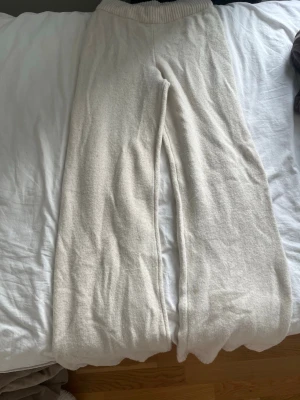Krämvita loungewear-byxor Amisu - Mysiga loungewear-byxor från Amisu i krämvit färg. Byxorna har en bred, ribbad midja och är tillverkade i ett mjukt stickat material. Perfekta för chill hemma eller när du vill vara extra bekväm.
