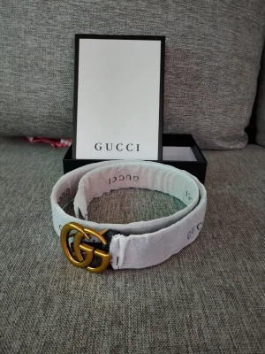 Gucci bälte 2298833 FU49X - Snyggt bälte från Gucci  med ikoniskt dubbelt GG-spänne i guld. Bältet har diskret Gucci-logga tryckt längs bandet och är tillverkat i skinn. Perfekt accessoar för att lyfta vilken outfit som helst. Bältet är 105CM