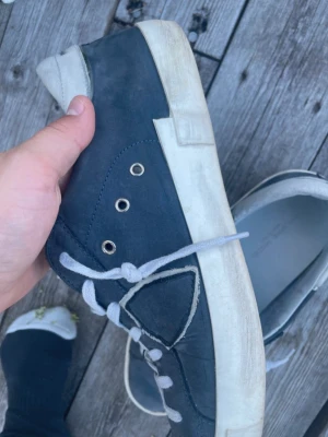 Philippe model  - Snygga mörkblå Philippe model med vit sula och vita skosnören. Skorna har silverfärgade öljetter och detaljer i vitt vid hälen. Ovandelen är i mockaliknande material och sulan är robust och platt. Perfekta för en avslappnad streetstil.