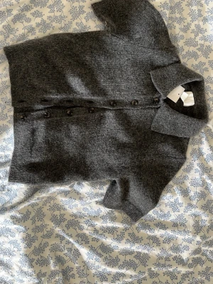 Mörkgrå stickad kofta med kort ärm - Mörkgrå stickad kofta med korta ärmar och knappar framtill. Enkel och stilren design som funkar till det mesta. Är lite stickig om man är känslig mot sådant. 