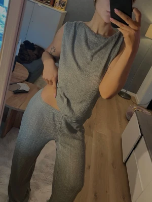 Grönt ribbat set - Säljer en snyggt grönt set i ribbat material med  djup draperad urringning man kan byta håll på så man har fram eller bak vid ryggen. Köpt delarna separat men säljer som ett set. Storlek 36. Använd endast 1 gång 