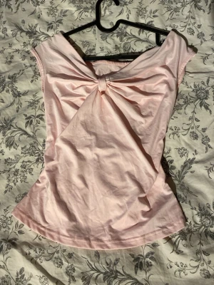 Ljusrosa topp med knutdetalj - Söt ljusrosa topp med knut framtill som ger en snygg draperad effekt. Toppen är ärmlös och har en mjuk, stretchig passform. Perfekt till jeans eller kjol för en trendig look.
