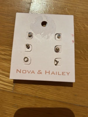 Set med små örhängen Nova & Hailey - Säljer ett set med sex små örhängen från Nova & Hailey. Setet innehåller olika former som stenar, ringar och månar i silverfärg och guldton. Perfekta för att mixa och matcha flera hål i öronen. Stilrena och trendiga accessoarer för dig som gillar minimalistiskt.