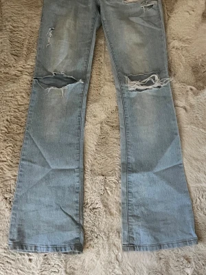 Ljusblå slitna jeans från YS Collection - Ljusblå jeans med slitningar och trasiga detaljer på knäna och låren från VS Collection. Klassisk femficksmodell med raka ben och snyggt tvättad denim. Däremot sitter knappen löst.💕