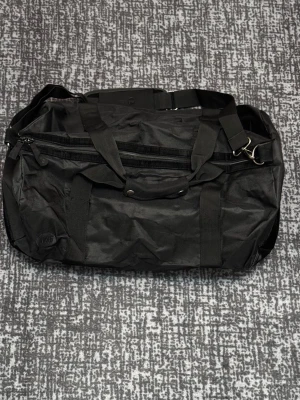 Mi-Pac duffelbag med axelrem - Säljer en Mi-Pac handväska/sportbag. Oanvänd – har endast legat vikt i garderob. Snygg design med mocka på underdelen som ger en stilren look. Perfekt som weekendbag, träningsväska eller vardagsväska.  Skick: Oanvänd Material: Textil med mockadetalj undertill  Hör gärna av dig vid frågor eller om du vill ha fler bilder