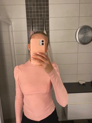 Ljusrosa ribbad långärmad topp - Säljer en ljusrosa ribbad topp med lång ärm och lätt puff vid axlarna. Toppen har en högre halsringning och är i ett mjukt, stretchigt material som sitter snyggt på kroppen. Perfekt att styla med jeans eller kjol. Använd några gånger men i fint skick. Bara att höra av dig om du undrar något eller vill ha fler bilder eller mått så löser jag det! 