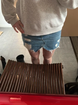 Blå jeanskjol med slitningar - Säljer min fina jeans kjol då den inte kommer till användning. Den är bara använd få tal gånger och är i bra skick💕