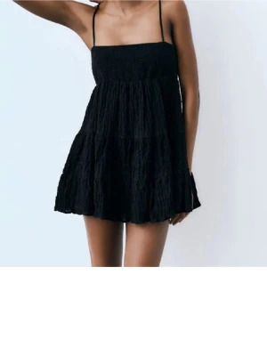 Svart kort klänning från Zara - Supersöt svart kort klänning med tunna axelband och volangig kjol. Klänningen har en smockad överdel och är i mycket bra skick