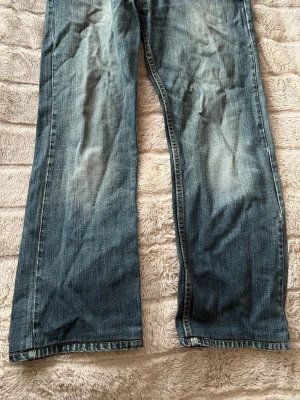 Levis 505 straight fit - Ett par blå straight fit jeans med snygg tvätt. Jeansen har klassisk femficksdesign. De är uppsydda så sitter som 30 i längd
