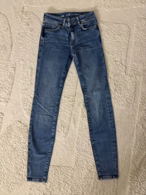 Blå skinny jeans - Säljer ett par blåa skinny jeans med klassisk femficksdesign och hög midja. Jeansen har smal passform hela vägen ner och är perfekta för en avslappnad och trendig look. Materialet är stretchigt för extra komfort.