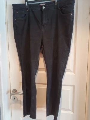 Svarta jeans med råa benslut - Svarta jeans från HM. Upplevs mer svarta i verkligheten. Storlek XXL. I mycket bra skick. Obs! Hund finns i hemmet. 