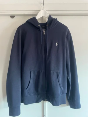 Mörkblå hoodie från Polo Ralph Lauren - Mörkblå hoodie med dragkedja från Polo Ralph Lauren. Hör av dig vid frågor!