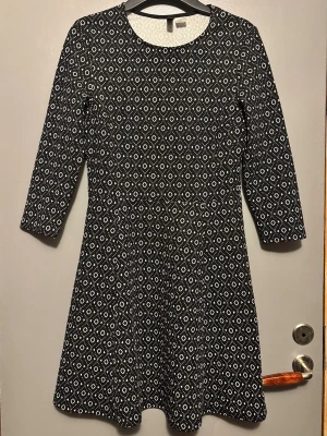 Svartvit mönstrad klänning H&M - Svartvit klänning från H&M med grafiskt rutmönster. Modellen är lätt utställd och slutar ovanför knät. Perfekt för dig som gillar stilrena mönster och enkel design.