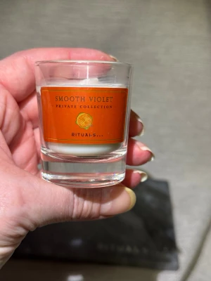 Nytt! Smooth Violet doftljus Rituals - Nytt! Litet doftljus från Rituals Private Collection med doften Smooth Violet. Ljuset är vitt och kommer i ett genomskinligt glas med orange etikett och gulddetaljer. Perfekt för att skapa mysig stämning hemma.