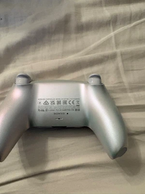 Vit Sony DualSense PS5 handkontroll - Säljer en vit Sony DualSense handkontroll till PlayStation 5. Kontrollern har en futuristisk design med svarta detaljer, inbyggd touchpad och ikoniska PlayStation-knappar. Tillverkad i plast med greppvänlig form och responsiva triggers. Perfekt för gaming på PS5.