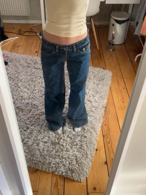 Blåa baggy jeans med låg midja - Säljer ett par blåa baggy jeans med låg midja och raka ben. Jeansen har klassiska fickor fram och bak samt tydliga sömmar. Perfekta för en avslappnad och trendig look. Materialet är denim i bomull.