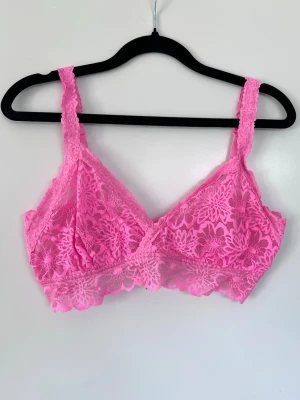 Rosa spets-bh / bralette utan bygel - Superfin rosa bh / bralette i spets med blommigt mönster, breda axelband och justerbar knäppning. Liten i storlek, passar typ S/M. Bra skick!