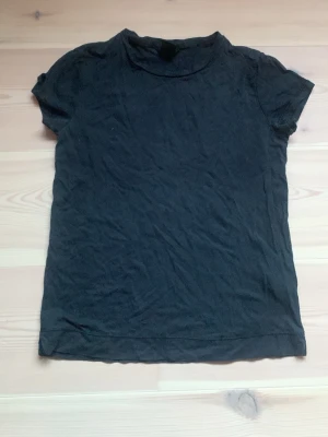 Svart t-shirt från Lindex XS - En basic svart t-shirt från Lindex i storlek XS. T-shirten har rund halsringning och korta ärmar. Tillverkad i mjuk bomull och passar perfekt till jeans eller kjol. Enkel och stilren design som funkar till allt.